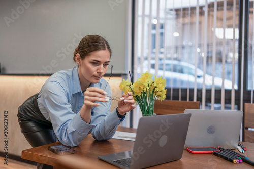Vászonkép Businesswoman professional glasses holds eyewear concentrating on work desk with laptops