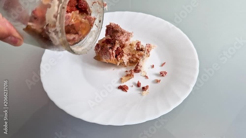A kitchen knife gently pushes slices of canned meat onto a plate, showing a simple food serving process. Practical preparation scene with everyday ingredients and casual dining