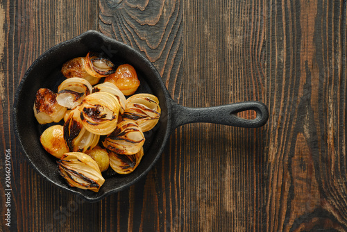Tableau sur toile Top view of cast iron skillet with roasted onions on wooden table