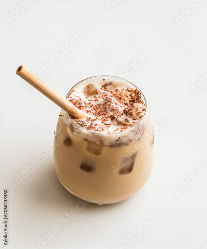 A glass of iced latte coffee with chocolate chips on a light background