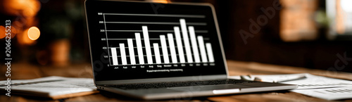 An office desk with a laptop displaying a presentation on passive investing, alongside notes and graphs, with a large empty area for copy space.