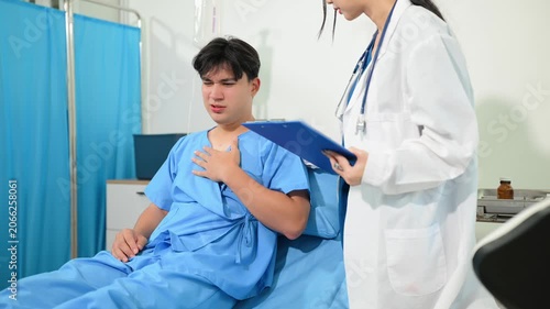 Professional female doctor discussing medical chart with an Asian patient in a hospital bed.