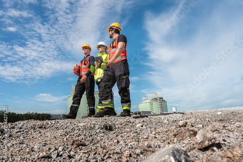 Construction worker team wearing safety gear inspecting industrial site outdoors