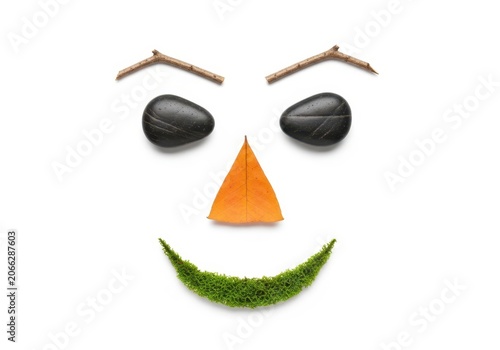 Funny face made of two acorns and pine twigs with a carrot nose and moss smile