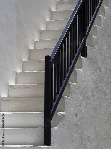 Obraz na plátne Blue bannister handrail on white stone steps on outside of building