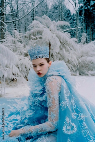 Woman in an sleek, shimmering, icy-blue gown with a crystal crown and a flowing train