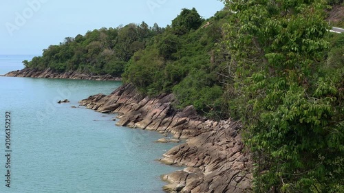 Aerial panoramic view of rugged tropical coastline in Khanom, Thailand. Turquoise sea, rocky cliffs, lush green vegetation, and pristine coastal landscape.