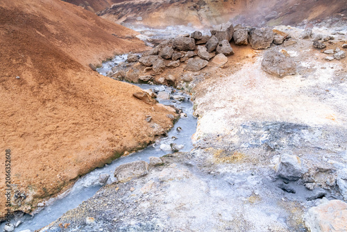 a stream of mud and boiling water crosses the colorful terrain in the geothermal area of Seltun in Reykjanes Peninsula in Iceland on a march day