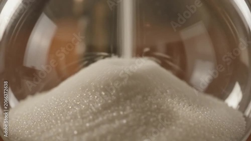 Fine white sand slowly running out of a beautiful vintage glass hourglass.