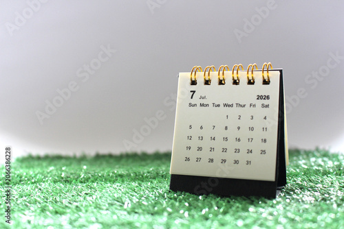 A monthly desk calendar for New Year 2026 placed on green grass with a white background.