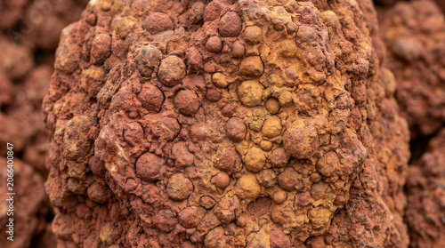 Close up of bauxite ore texture with red rocky nodules and porous mineral surface for natural geology background