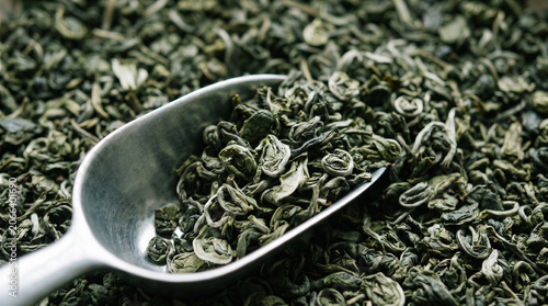 Dry green tea leaves in metal scoop, top view of organic healthy herbal drink ingredients for brewing tea, antioxidant product