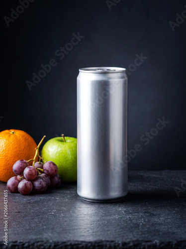 Blank aluminum beverage can with fresh fruit on dark stone surface