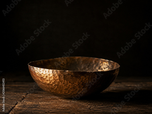 Hammered copper bowl with warm patina and rustic texture on wooden surface evoking cozy, vintage kitchen atmosphere