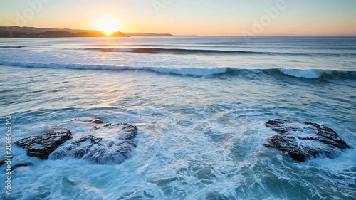 Golden sunset over ocean waves crashing against dark coastal rocks