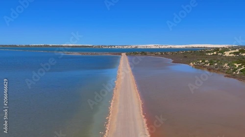 Aerial drone shot flying forward along the straight road dividing the pink and blue waters of Point Sinclair Pink Lake