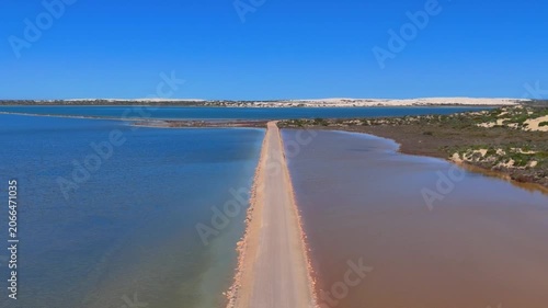 Aerial drone footage ascending over the causeway that splits Point Sinclair Pink Lake into pink and blue sections