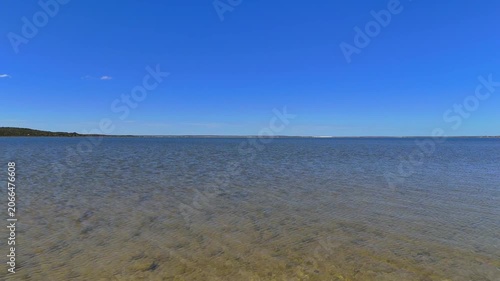 Aerial drone shot flying low over the pink water of Point Sinclair Pink Lake, crossing the road into blue water