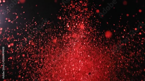 Explosion of vibrant red glitter particles against a dark black background