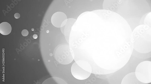 Abstract black and white bokeh background with soft glowing light circles