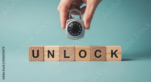 Hand holding padlock above wooden blocks spelling UNLOCK.