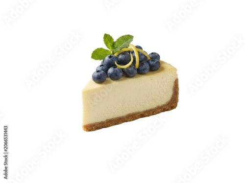 A slice of cheesecake topped with blueberries and mint on a white background.