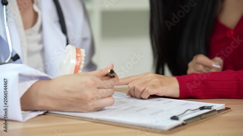 Professional dentist consulting with a patient in a modern dental clinic, explaining teeth restoration, prosthetic options, oral health care, treatment plans, and dental hygiene during a routine check