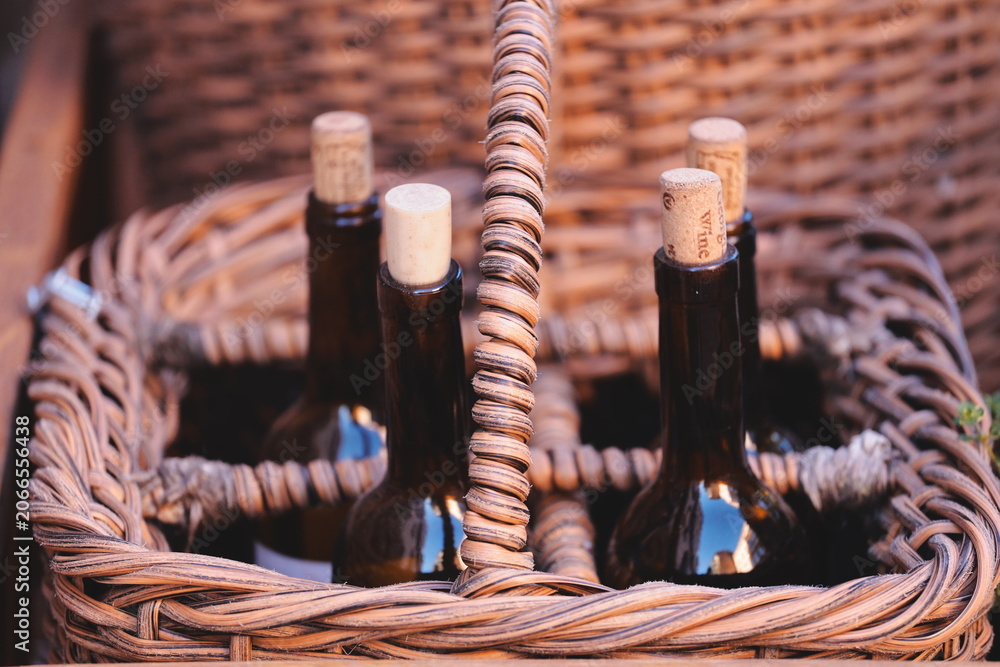 Fototapeta premium Three bottles of wine in a woven wicker basket