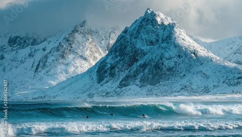 Surfers Brave Icy Waves Against Majestic Snow-Capped Mountain Backdrop.