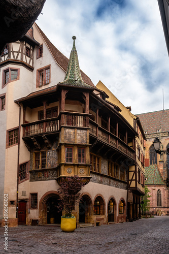 Ornate oriel window over narrow street showcasing carved woodwork, balcony detail, textured facade and historic craftsmanship under soft sky