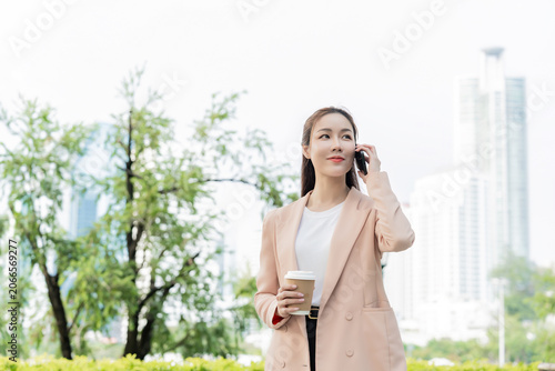 Portrait of Asian Businesswoman Talking on Phone with Coffee Outdoors.