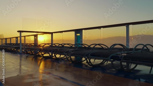 Empty lounge chairs on cruise ship deck at sunrise, copy space