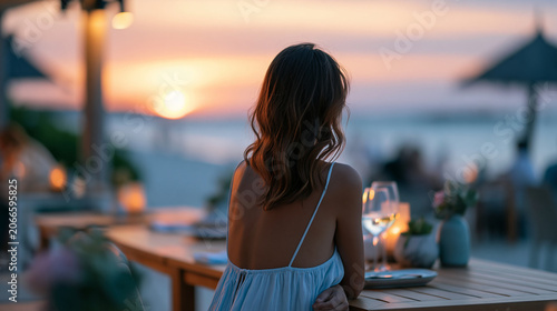 Faceless serene woman seated at a beachside table during a beautiful sunset, calm coastal dining atmosphere, defocused sunset beach in background, beachside dining concept