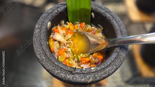 Fresh Indonesian sambal made with shallots, chilies, and herbs served in a traditional stone bowl. Flavorful condiment perfect for enhancing local dishes