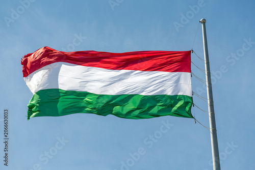 Hungarian flag waves in the wind against a clear sky with no clouds during a sunny day