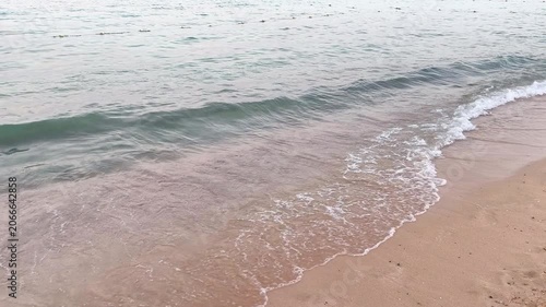 Calm ocean, sandy beach and small waves. Water surface with the sandy shore, small waves. Travel video from the beach. Morning by the sea.