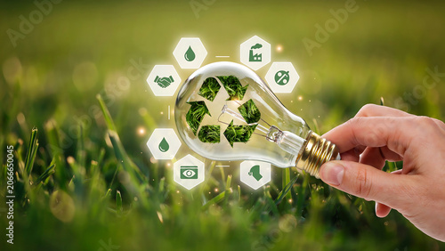 Hand Holding Light Bulb with Green Grass Recycle Symbol and Sustainability Icons for Renewable Energy Eco Concept