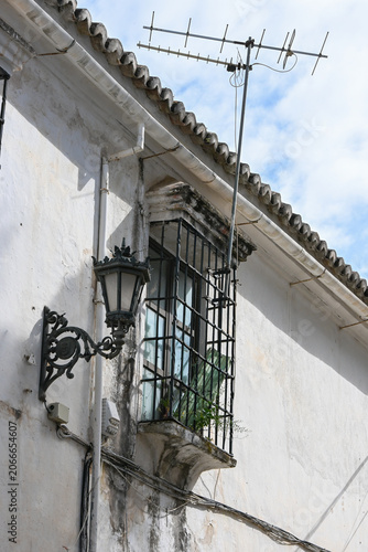 traditional wrought iron balcony and street lamp on a whitewashed house in Ronda, Spain