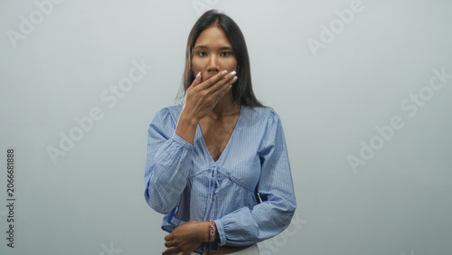 Foto Thai woman with hand covering mouth and closed eyes in studio wearing blue blouse; fatigue restraint