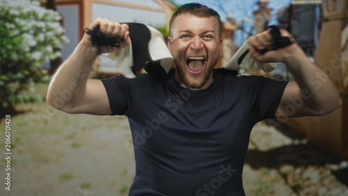 Fotografie Man roaring with open mouth and raised arms holding black and white scarf on street; celebration support