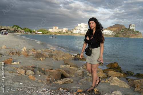 Konstfotografi Una hermosa joven pasea por la arena de la playa con ropa informal al atardecer