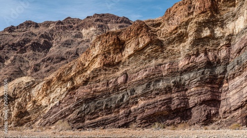 Detailed geological fault scarp showcasing distinct exposed rock layers and stratified rock formations under a clear blue sky.