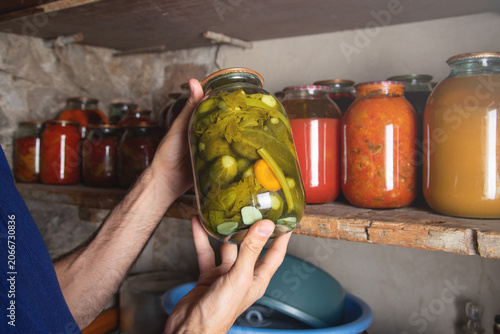 Man holding jar of canned at pantry.