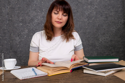 A woman reading a book at her desk at home, studying, professional development