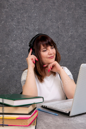 A young woman wearing headphones and studying online on a laptop at home