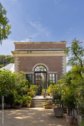 Historic Herbgarden (Kruidtuin) in Leuven, Belgium with greenhouse entrance and lush potted plants