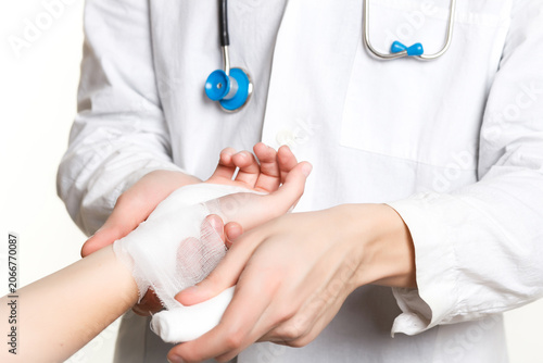 Obraz na płótnie Doctor bandaging child hand injury with first aid