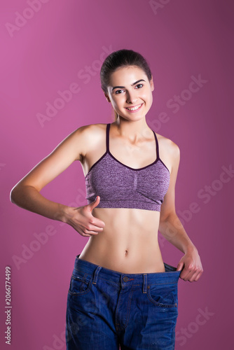 Photography Slim woman showing weight loss success in oversized jeans