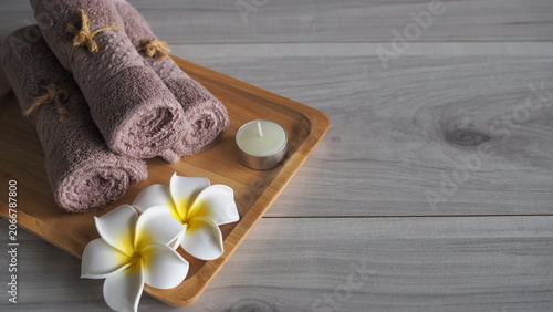Foto Luxury spa still life with rolled towels, lotion dispenser, tropical flowers and candle on wooden tray