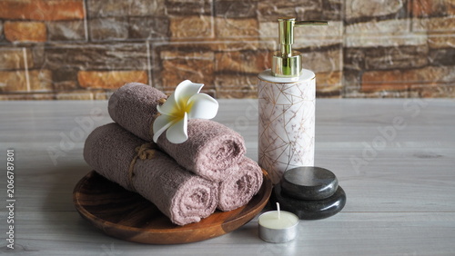 Foto Luxury spa still life with rolled towels, lotion dispenser, tropical flowers and candle on wooden tray
